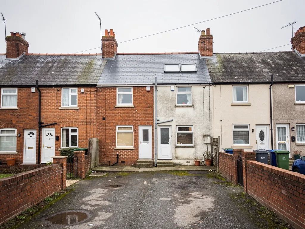 Back yards of brick and pebbledashed terraces around a shared lane