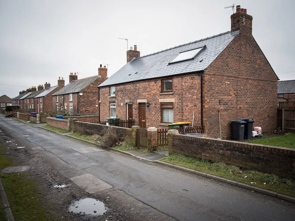 Brick terraced houses with a roof window along a damp lane
