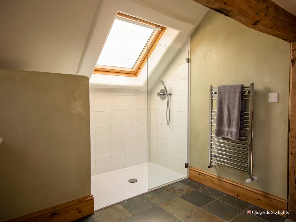 Shower room with a heated towel rail beneath a pine roof window