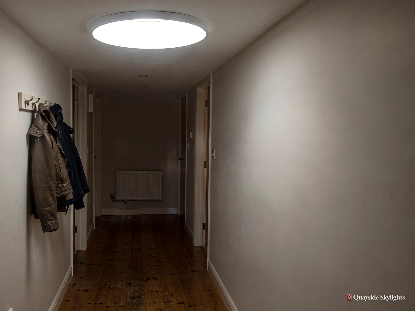 Dim hallway with coats on hooks and a round ceiling light