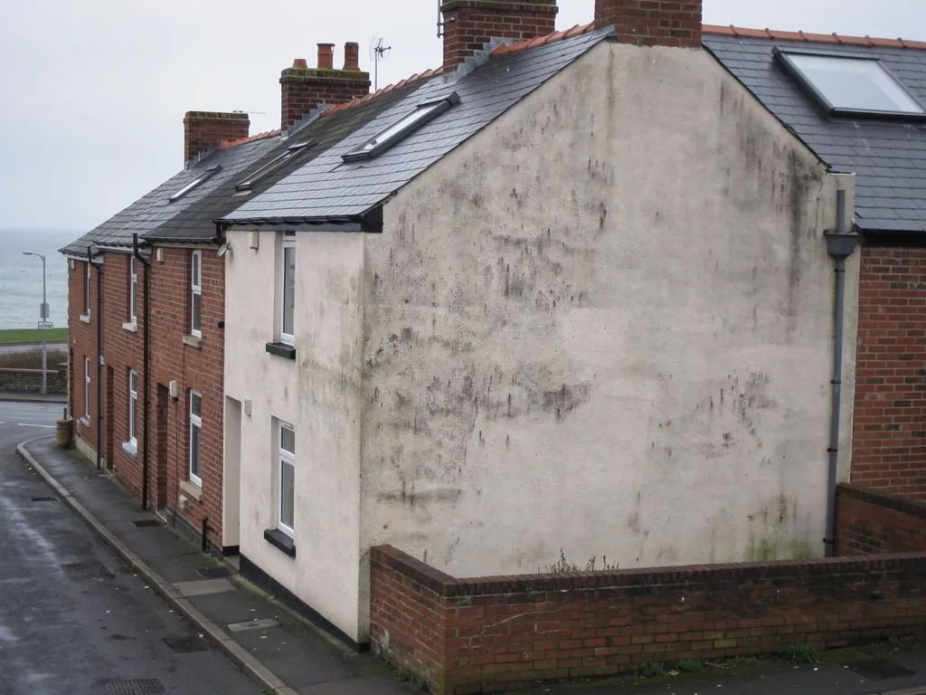 End terrace with a weathered rendered gable and roof windows