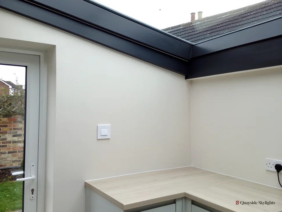 Room corner with a pale worktop and door beneath a glazed roof edge